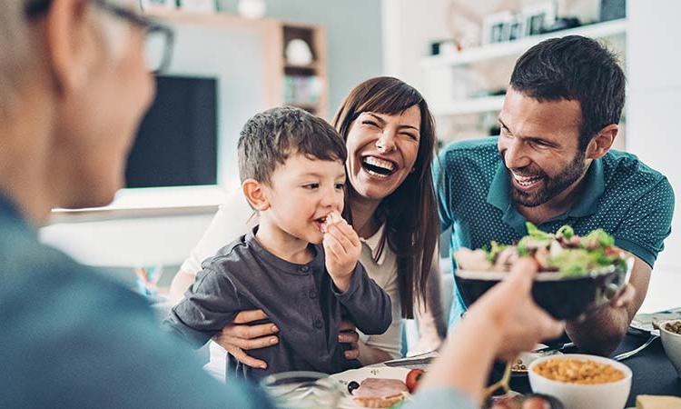 Family laughing and eating dinner together.